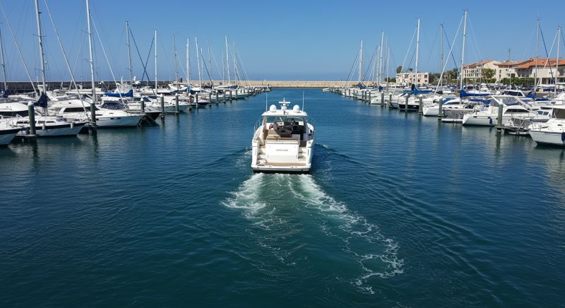 White sport yacht performing docking maneuver in tight marina space